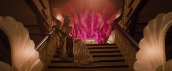 Movie still from “Booksmart” (2019), directed by Olivia Wilde – A woman in a gold dress sitting on the stairs; Wide shot, Low angle