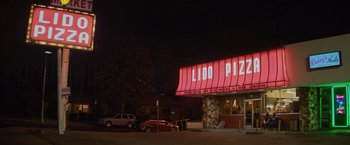 Movie still from “Booksmart” (2019), directed by Olivia Wilde – A lit up sign for a pizza restaurant at night; Extreme Wide shot, Low angle