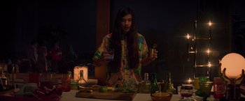 Movie still from “Booksmart” (2019), directed by Olivia Wilde – A person standing at a table holding a drink; Medium shot, High angle