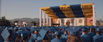 Movie still from “Booksmart” (2019), directed by Olivia Wilde – A crowd of people in blue caps and gowns at a graduation ceremony; Extreme Wide shot, High angle