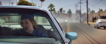 Movie still from “Booksmart” (2019), directed by Olivia Wilde – A woman driving a car on the side of the road; Medium shot, Low angle