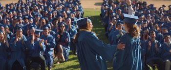 Movie still from “Booksmart” (2019), directed by Olivia Wilde – A group of people in graduation caps and gowns; Wide shot, Over the shoulder angle