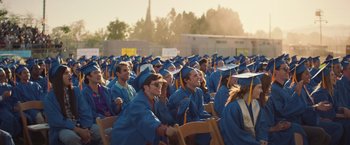 Movie still from “Booksmart” (2019), directed by Olivia Wilde – A group of people sitting in graduation caps and gowns; Wide shot, Low angle