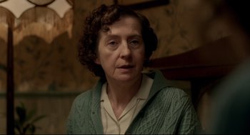 Movie still from “Brooklyn” (2015), directed by John Crowley – An older woman wearing a green sweater and looking at the camera; Close Up shot, Over the shoulder angle