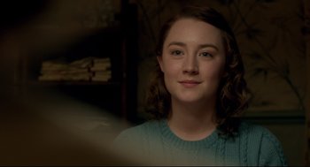 Movie still from “Brooklyn” (2015), directed by John Crowley – A young woman in a blue sweater is smiling for the camera; Close Up shot, Over the shoulder angle