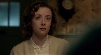 Movie still from “Brooklyn” (2015), directed by John Crowley – A woman in a white shirt and jacket looking at the camera; Close Up shot, Over the shoulder angle