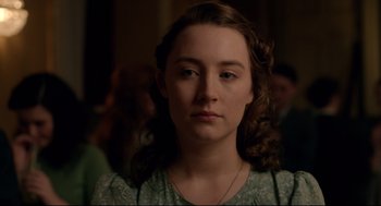 Movie still from “Brooklyn” (2015), directed by John Crowley – A young woman with long brown hair wearing a green dress; Close Up shot, Over the shoulder angle