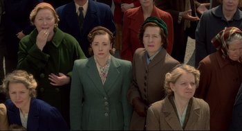 Movie still from “Brooklyn” (2015), directed by John Crowley – A group of people standing next to each other wearing suits; Medium shot, High angle