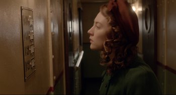 Movie still from “Brooklyn” (2015), directed by John Crowley – A young woman looking out of a window in a room; Close Up shot, Over the shoulder angle