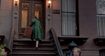 Movie still from “Brooklyn” (2015), directed by John Crowley – A woman in a green coat carrying a suitcase down the steps; Wide shot, High angle