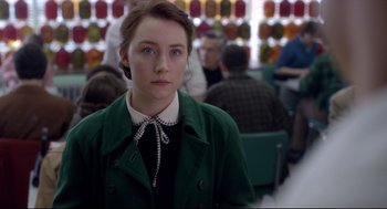 Movie still from “Brooklyn” (2015), directed by John Crowley – A woman in a green jacket and a black shirt; Close Up shot, Over the shoulder angle