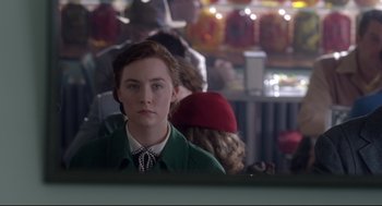 Movie still from “Brooklyn” (2015), directed by John Crowley – A woman in a green coat and a red hat; Close Up shot, Over the shoulder angle