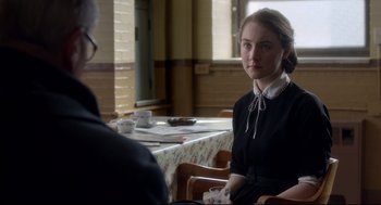 Movie still from “Brooklyn” (2015), directed by John Crowley – A woman sitting at a table with a cup of coffee; Medium shot, Over the shoulder angle