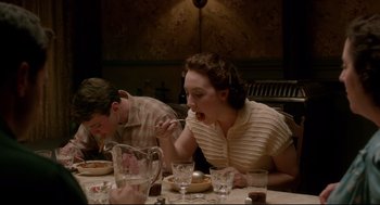 Movie still from “Brooklyn” (2015), directed by John Crowley – A woman is eating at a table with a boy; Medium shot, High angle