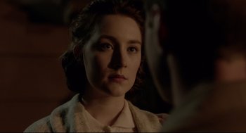 Movie still from “Brooklyn” (2015), directed by John Crowley – A young woman looking at the camera with a serious look on her face; Close Up shot, Over the shoulder angle