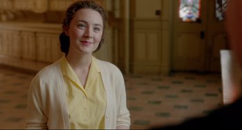 Movie still from “Brooklyn” (2015), directed by John Crowley – A woman in a yellow shirt and a white sweater; Close Up shot, Over the shoulder angle