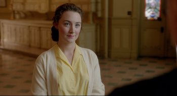 Movie still from “Brooklyn” (2015), directed by John Crowley – A woman in a yellow shirt and a white sweater; Close Up shot, Over the shoulder angle