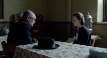 Movie still from “Brooklyn” (2015), directed by John Crowley – An older man and a young woman sitting at a table; Medium shot, Over the shoulder angle