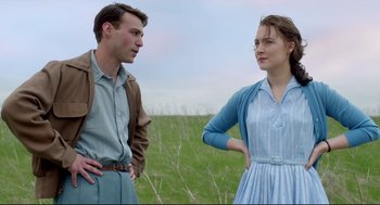 Movie still from “Brooklyn” (2015), directed by John Crowley – A man and a woman standing next to each other in a field; Medium shot, Low angle