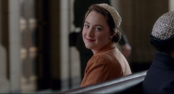 Movie still from “Brooklyn” (2015), directed by John Crowley – A young woman wearing a white hat and a brown dress; Close Up shot, Over the shoulder angle