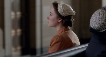 Movie still from “Brooklyn” (2015), directed by John Crowley – A young woman wearing a white hat sitting on a bench; Close Up shot, High angle