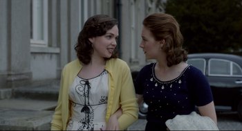 Movie still from “Brooklyn” (2015), directed by John Crowley – Two young women standing next to each other on the sidewalk; Medium shot, Over the shoulder angle