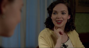 Movie still from “Brooklyn” (2015), directed by John Crowley – A young woman smiles while sitting at a table; Close Up shot, Over the shoulder angle