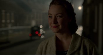 Movie still from “Brooklyn” (2015), directed by John Crowley – A young woman is standing in the dark; Close Up shot, Over the shoulder angle