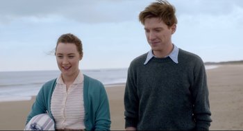 Movie still from “Brooklyn” (2015), directed by John Crowley – A man and a woman standing next to each other on the beach; Medium shot, Over the shoulder angle