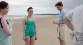 Movie still from “Brooklyn” (2015), directed by John Crowley – A man and a woman standing on a sandy beach; Medium shot, Over the shoulder angle