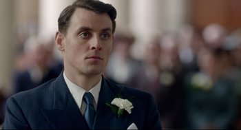 Movie still from “Brooklyn” (2015), directed by John Crowley – A man in a suit and tie with a flower in his lapel; Close Up shot, Low angle