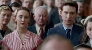 Movie still from “Brooklyn” (2015), directed by John Crowley – A man and a woman standing next to each other in a crowd; Close Up shot, Over the shoulder angle