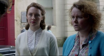 Movie still from “Brooklyn” (2015), directed by John Crowley – Two women standing next to each other in front of a building; Close Up shot, Over the shoulder angle
