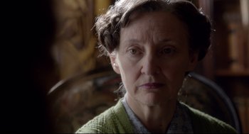 Movie still from “Brooklyn” (2015), directed by John Crowley – An older woman wearing a green sweater looking at the camera; Close Up shot, Over the shoulder angle