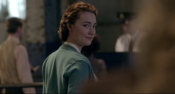 Movie still from “Brooklyn” (2015), directed by John Crowley – A young woman in a green sweater is looking at the camera; Close Up shot, Over the shoulder angle