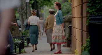 Movie still from “Brooklyn” (2015), directed by John Crowley – A woman in a floral dress is walking down the sidewalk; Wide shot, Over the shoulder angle