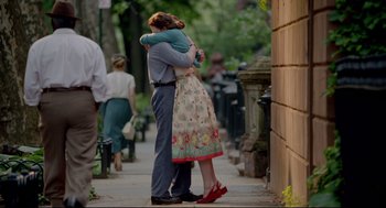 Movie still from “Brooklyn” (2015), directed by John Crowley – A man and a woman hugging on a sidewalk; Wide shot, Over the shoulder angle