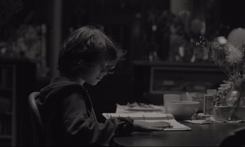 Movie still from “C'mon C'mon” (2021), directed by Mike Mills – A young boy sitting at a table writing on a piece of paper; Medium shot, Over the shoulder angle