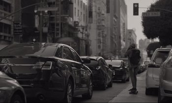 Movie still from “C'mon C'mon” (2021), directed by Mike Mills – A man skateboarding down a busy city street; Wide shot, Low angle