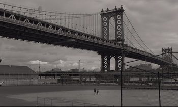 Movie still from “C'mon C'mon” (2021), directed by Mike Mills – Two people walking across a field under a bridge; Extreme Wide shot, High angle