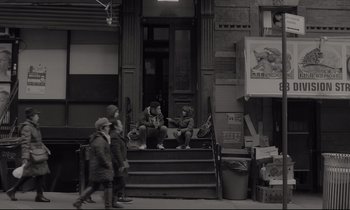 Movie still from “C'mon C'mon” (2021), directed by Mike Mills – A group of people sitting on steps in front of a building; Wide shot, Over the shoulder angle
