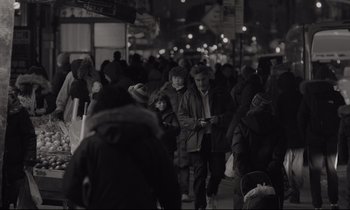 Movie still from “C'mon C'mon” (2021), directed by Mike Mills – A crowd of people walking down a street at night; Wide shot, Over the shoulder angle