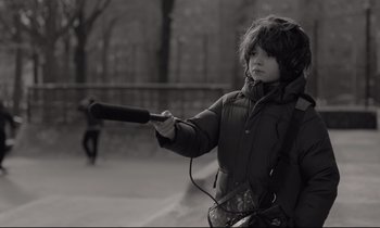 Movie still from “C'mon C'mon” (2021), directed by Mike Mills – A young boy holding a baseball bat and wearing ear phones; Close Up shot, Over the shoulder angle