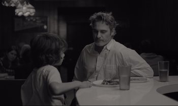 Movie still from “C'mon C'mon” (2021), directed by Mike Mills – A man sitting at a dinner table with a child; Medium shot, Over the shoulder angle