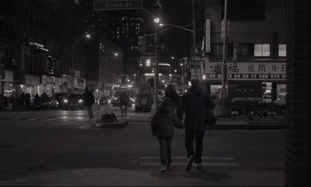 Movie still from “C'mon C'mon” (2021), directed by Mike Mills – Two people crossing a street at night in the dark; Wide shot, Over the shoulder angle