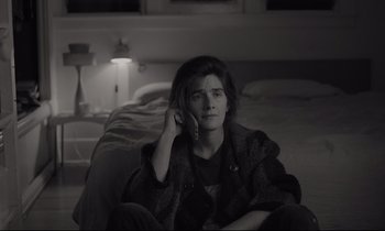Movie still from “C'mon C'mon” (2021), directed by Mike Mills – A woman sitting on a bed talking on a phone; Medium shot, High angle