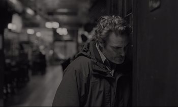 Movie still from “C'mon C'mon” (2021), directed by Mike Mills – A black and white photo of a man leaning against a wall; Close Up shot, Over the shoulder angle