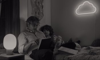 Movie still from “C'mon C'mon” (2021), directed by Mike Mills – A man and a woman sitting on a bed reading; Medium shot, Over the shoulder angle