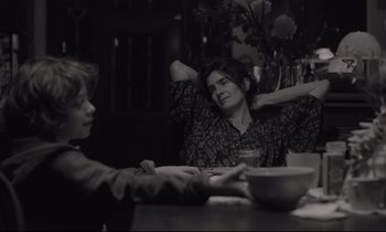 Movie still from “C'mon C'mon” (2021), directed by Mike Mills – A woman sitting at a table next to a bowl of food; Medium shot, Over the shoulder angle