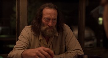Movie still from “CODA” (2021), directed by Sian Heder – A man with long hair and a beard sitting at a table; Close Up shot, Low angle